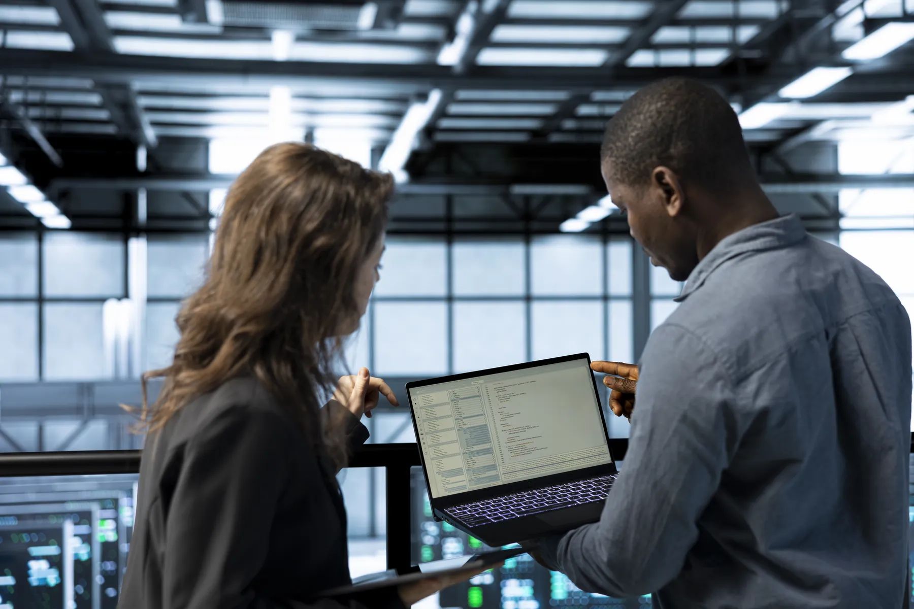 Twee IT-experts bekijken samen code op een laptop in een serverruimte